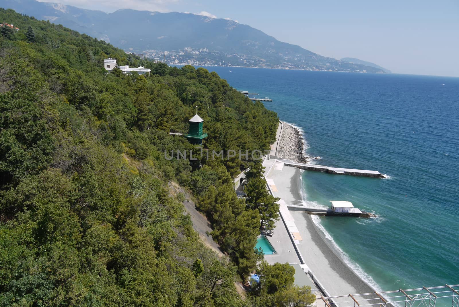 a sea bay near the green mountains with sandy beaches and pier ships