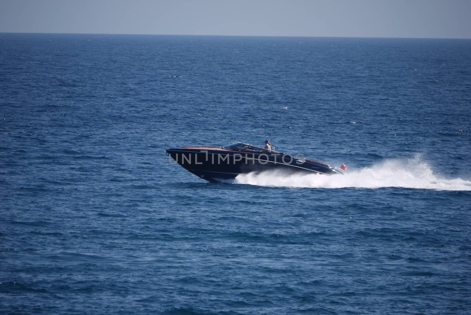 Quick boat with vacationers, rushing along the beautiful endless blue sea