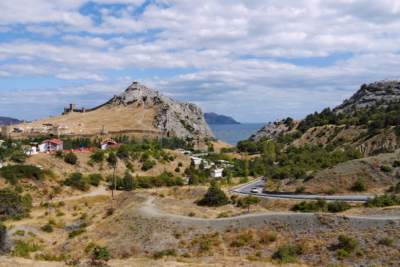 Beautiful scenery of the area with valleys and hills with the road of the houses standing among them standing among the trees and the far away sea.