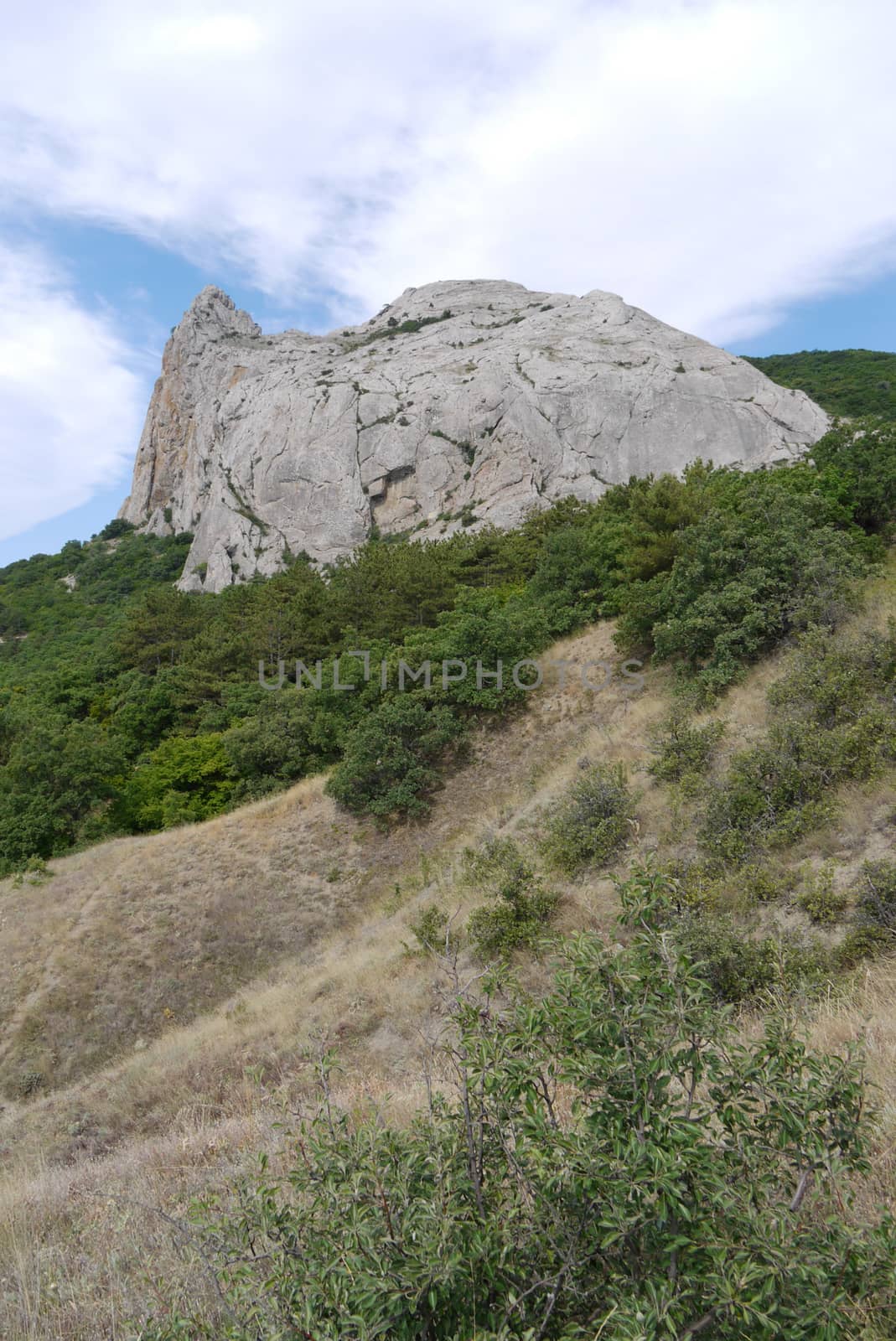 a stone hill with a spire on a hill with dry sunburned grass and by Adamchuk