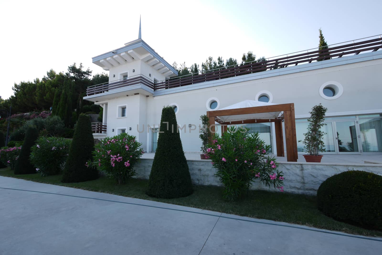 A beautiful, large, white villa with a roof terrace and greenery around