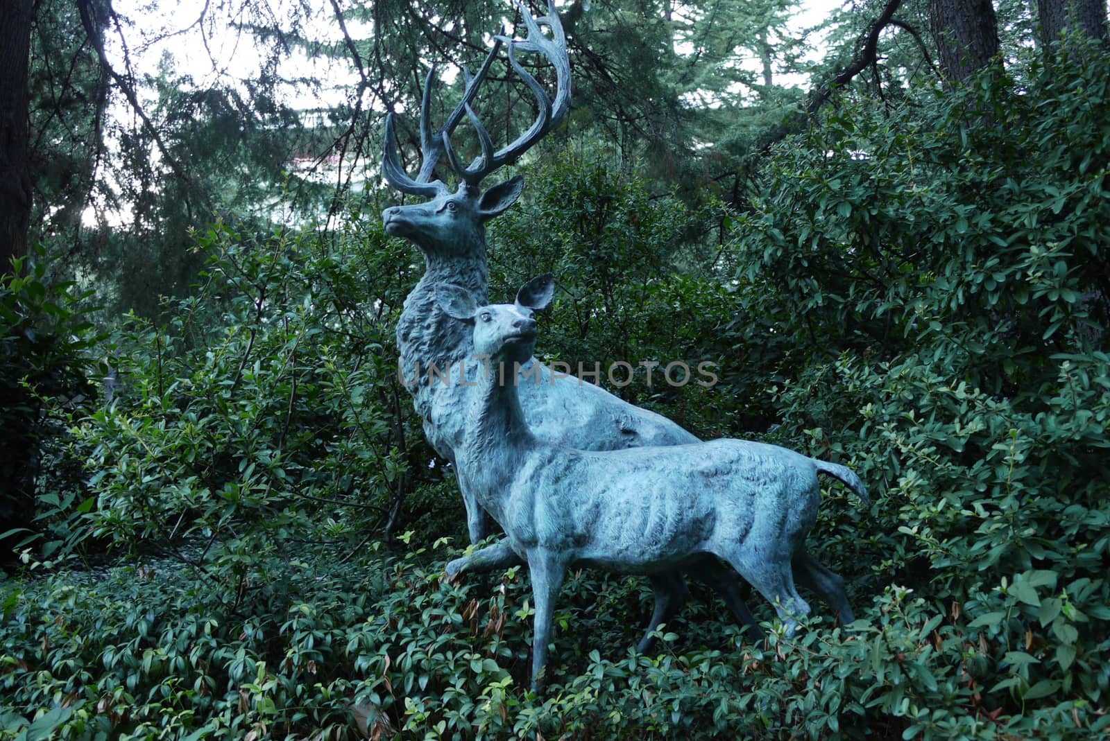 Decorative sculpture depicting two forest animals against a background of green bushes and trees