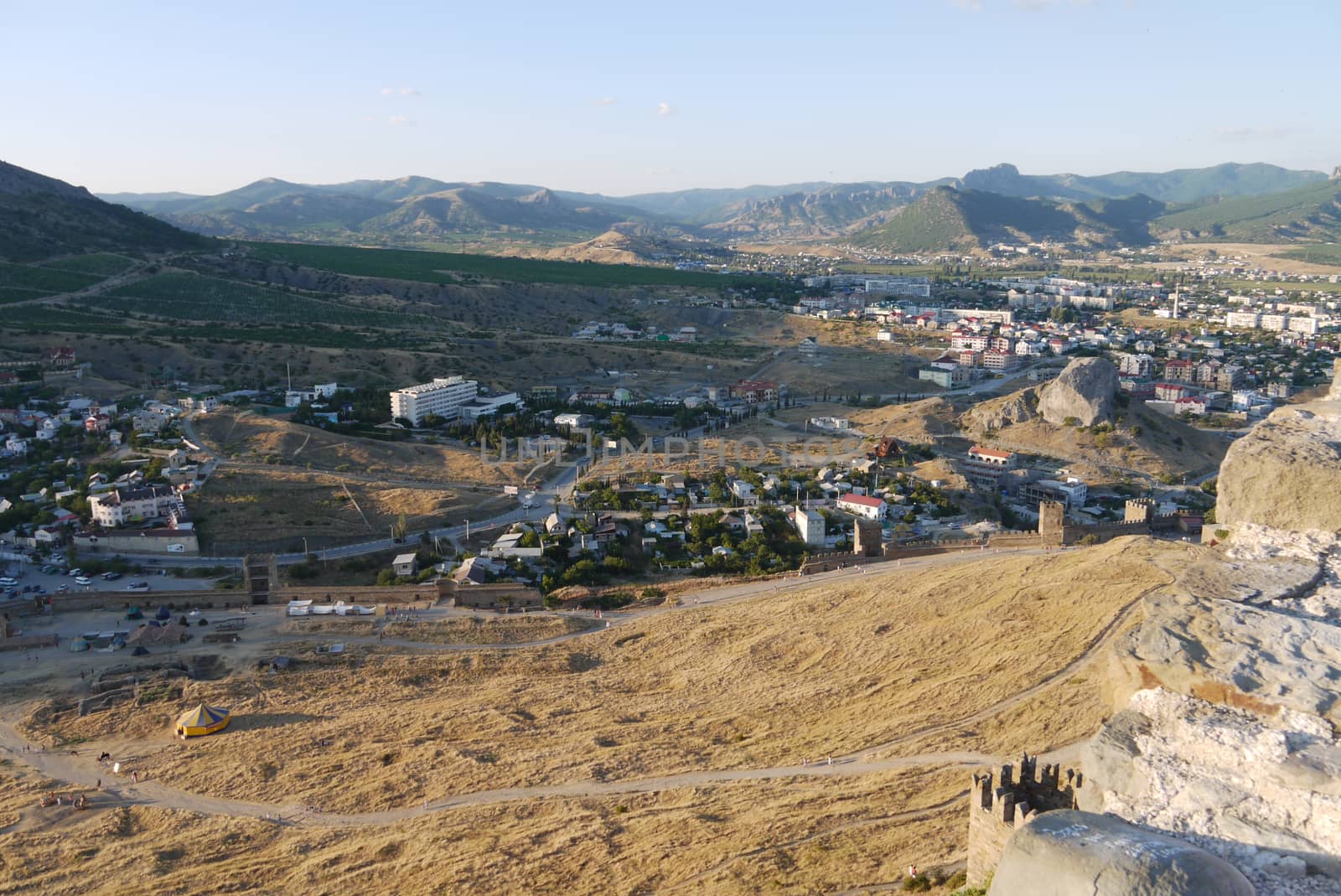 a small cozy town on the background of large covered with trees mountains by Adamchuk