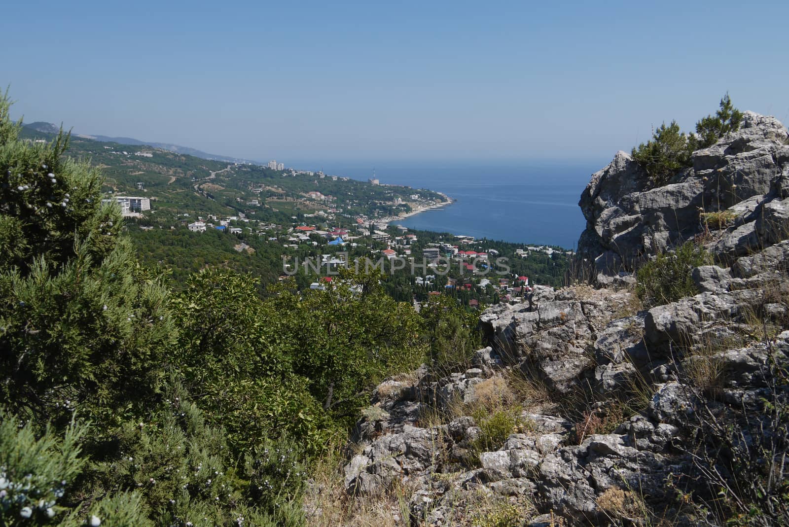 small grass-covered rocks on the background of a beautiful coastal town by Adamchuk