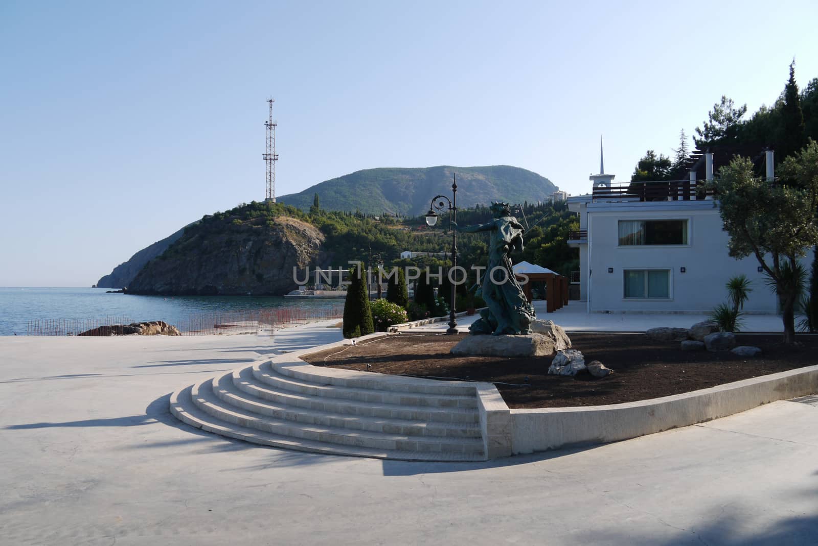 A small park with a sculpture of Neptune on the rocks and a beautiful view of the sea and mountains by Adamchuk