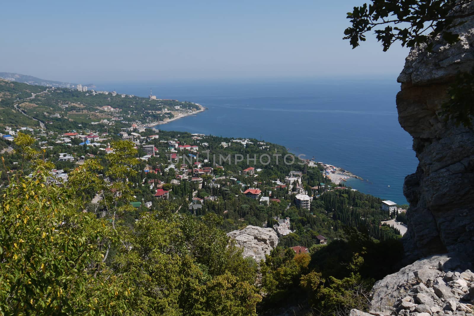 small grass-covered rocks on the background of a beautiful coastal town by Adamchuk