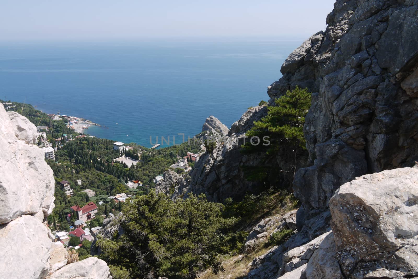 a small rock on the background of a beautiful quiet coastal town under a blue sky by Adamchuk