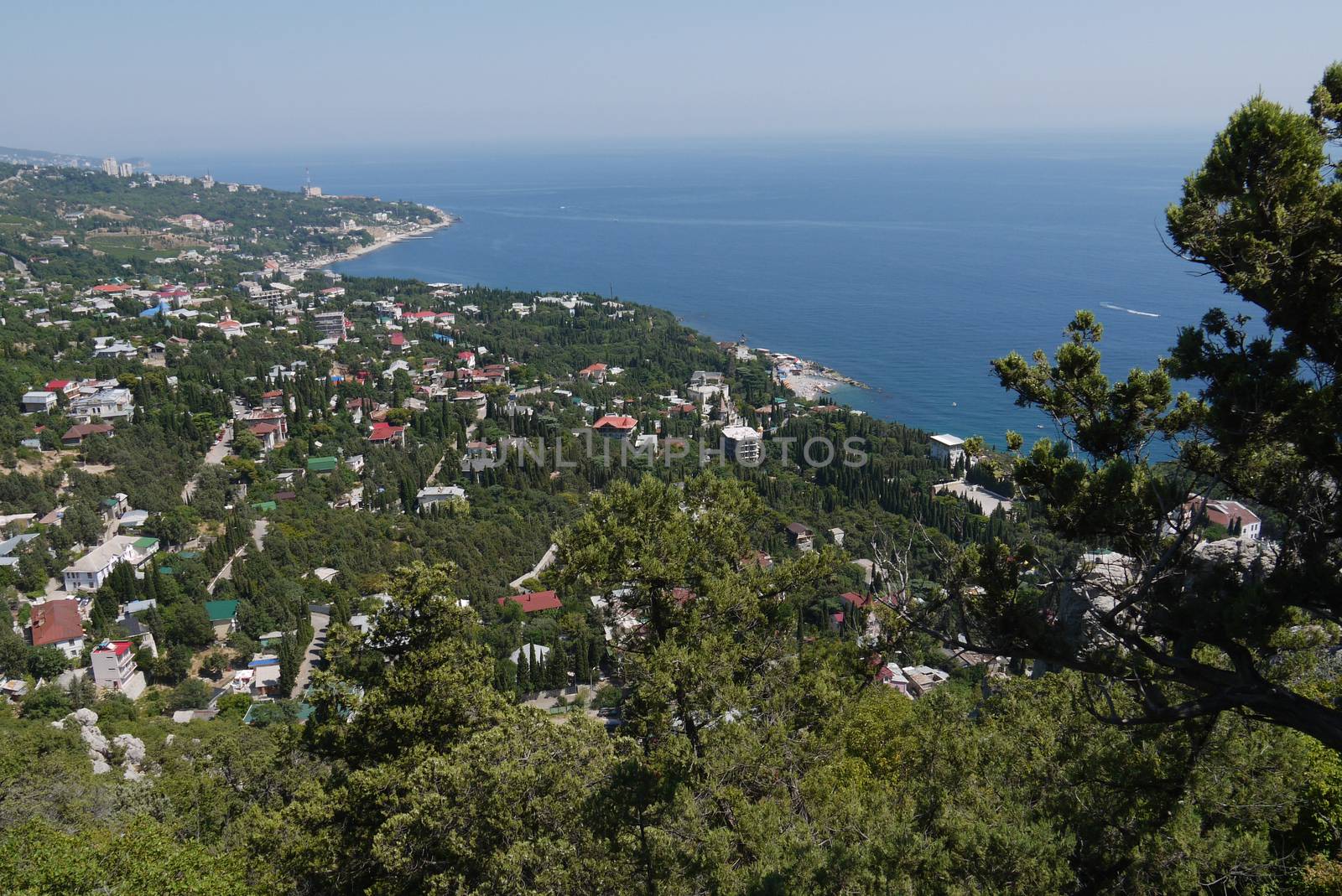 small grass-covered rocks on the background of a beautiful coastal town by Adamchuk