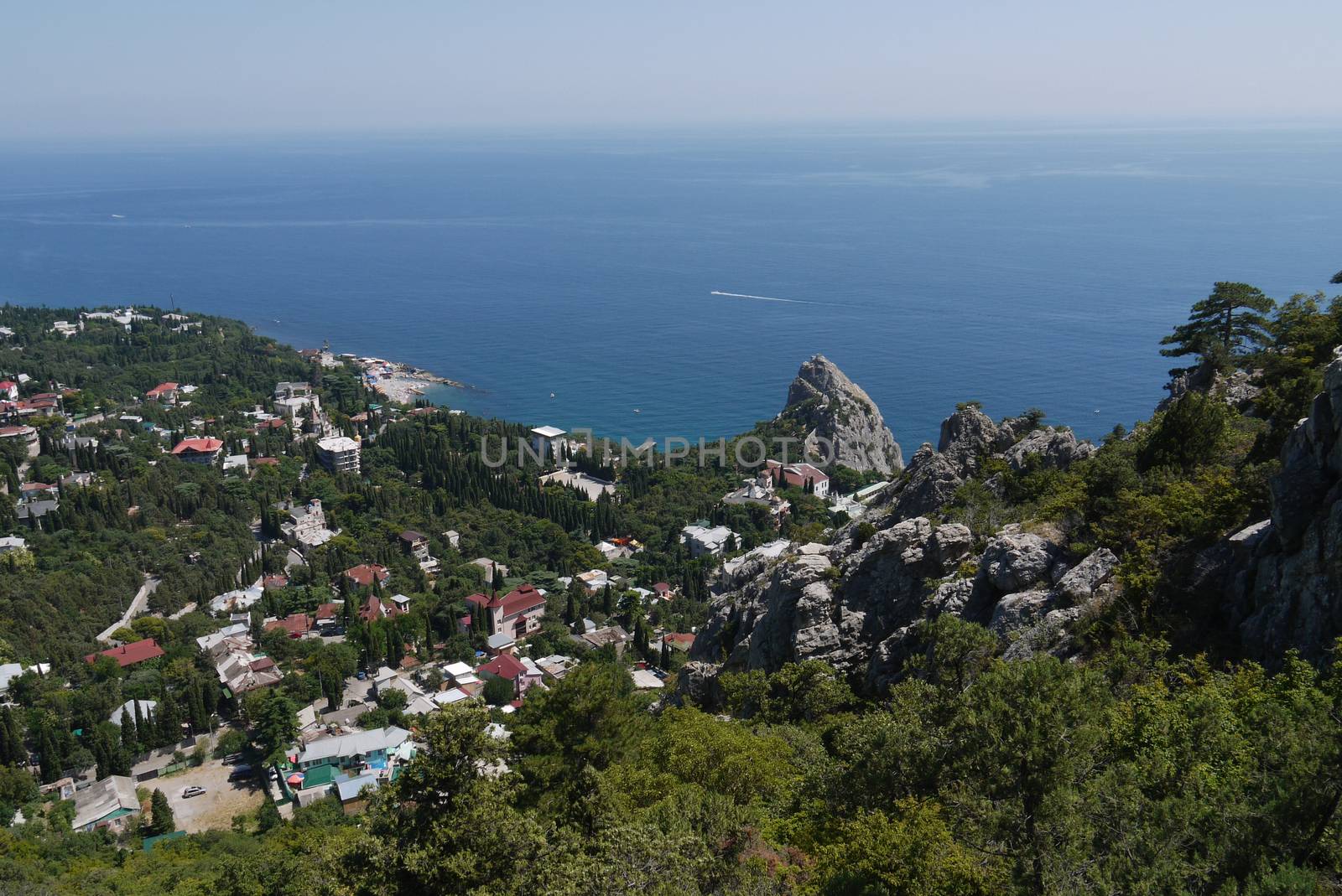 small grass-covered rocks on the background of a beautiful coastal town by Adamchuk