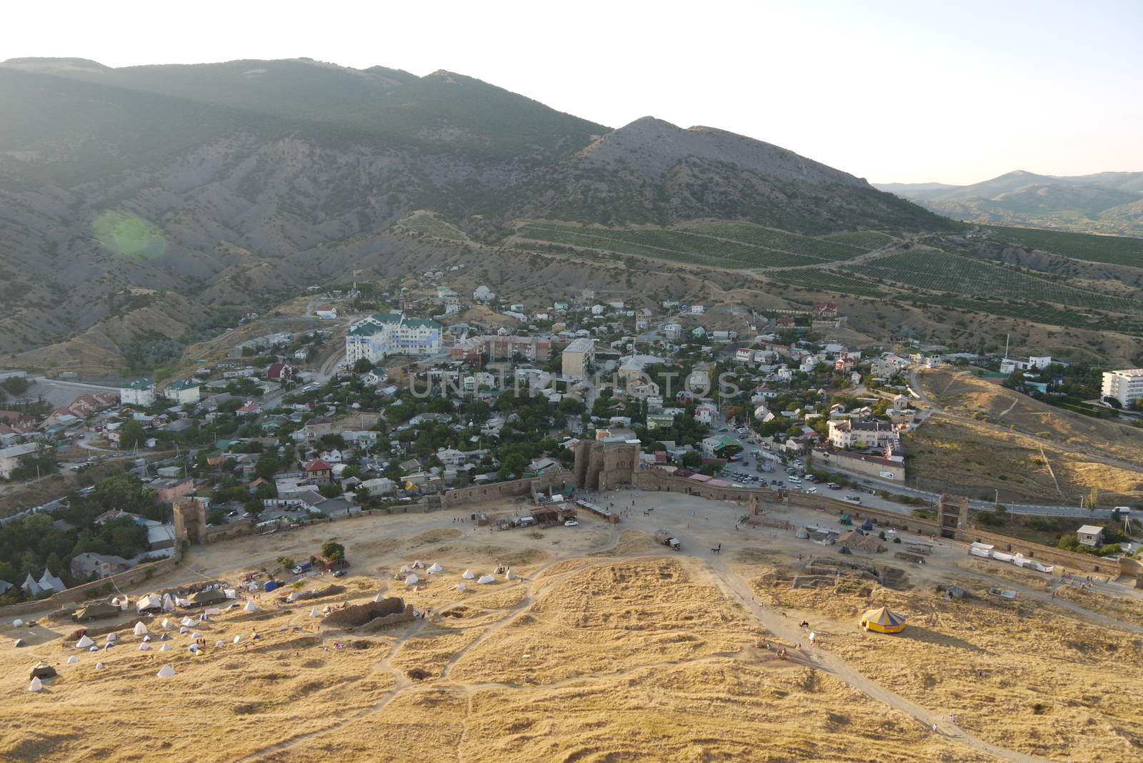 a small cozy town on the background of large covered with trees mountains by Adamchuk