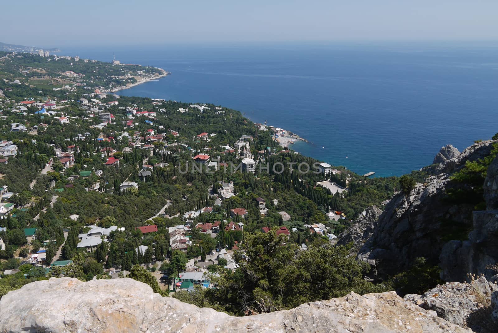 a small rock on the background of a beautiful quiet coastal town under a blue sky by Adamchuk