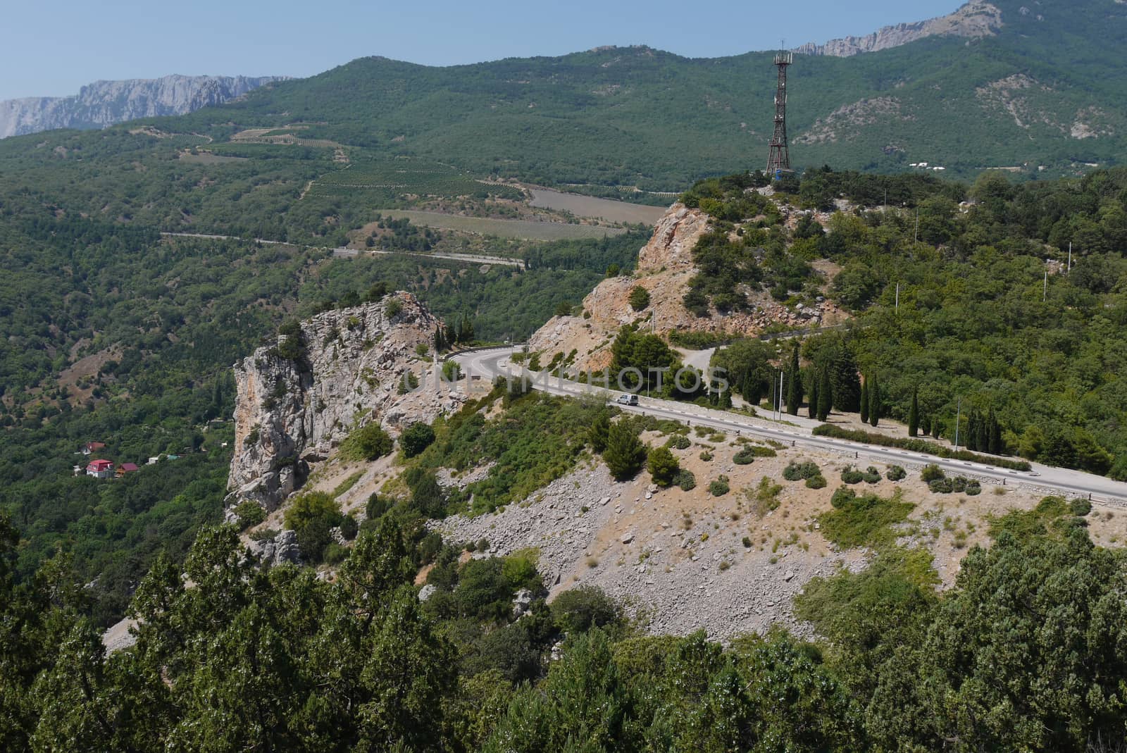 twisted rocky road against the background of high mountains covered with trees