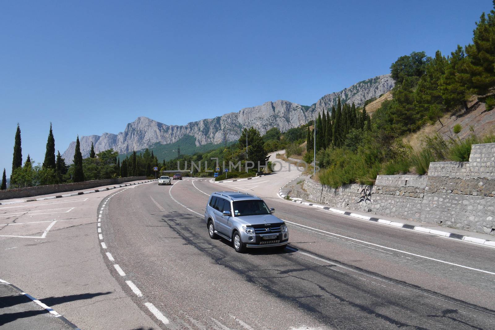 the road is twisted on the background of the steep cliffs surrounded by dense forest