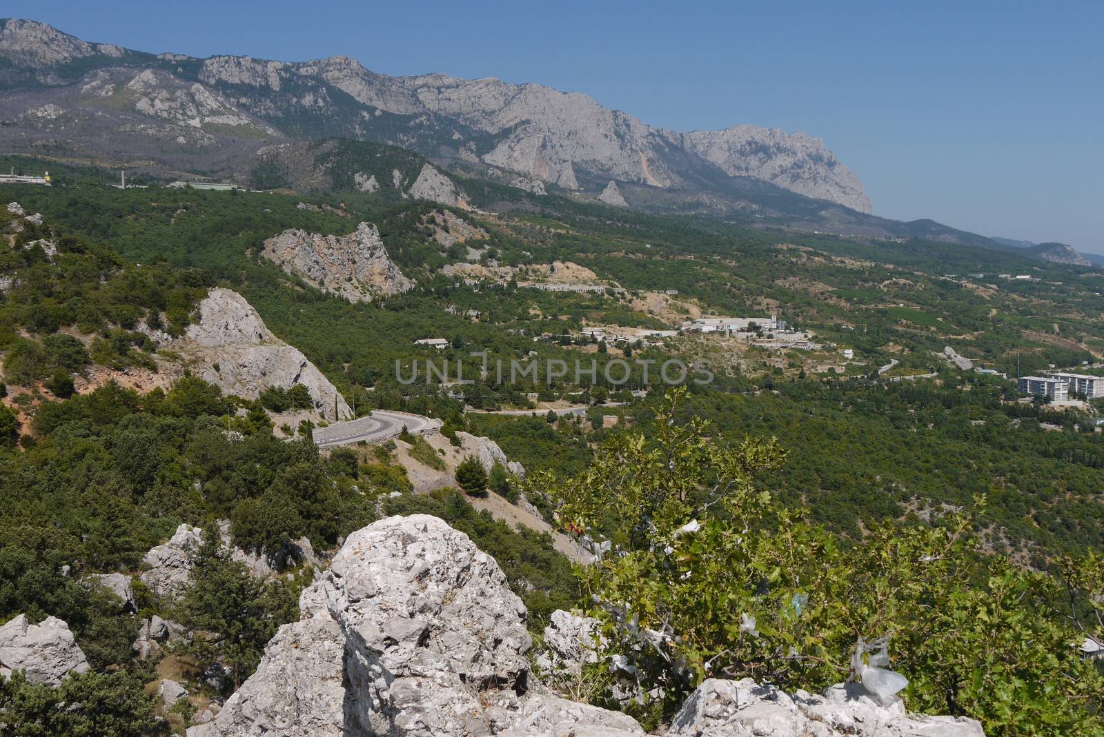 the road is twisted in the middle of the large, long mountains covered with trees