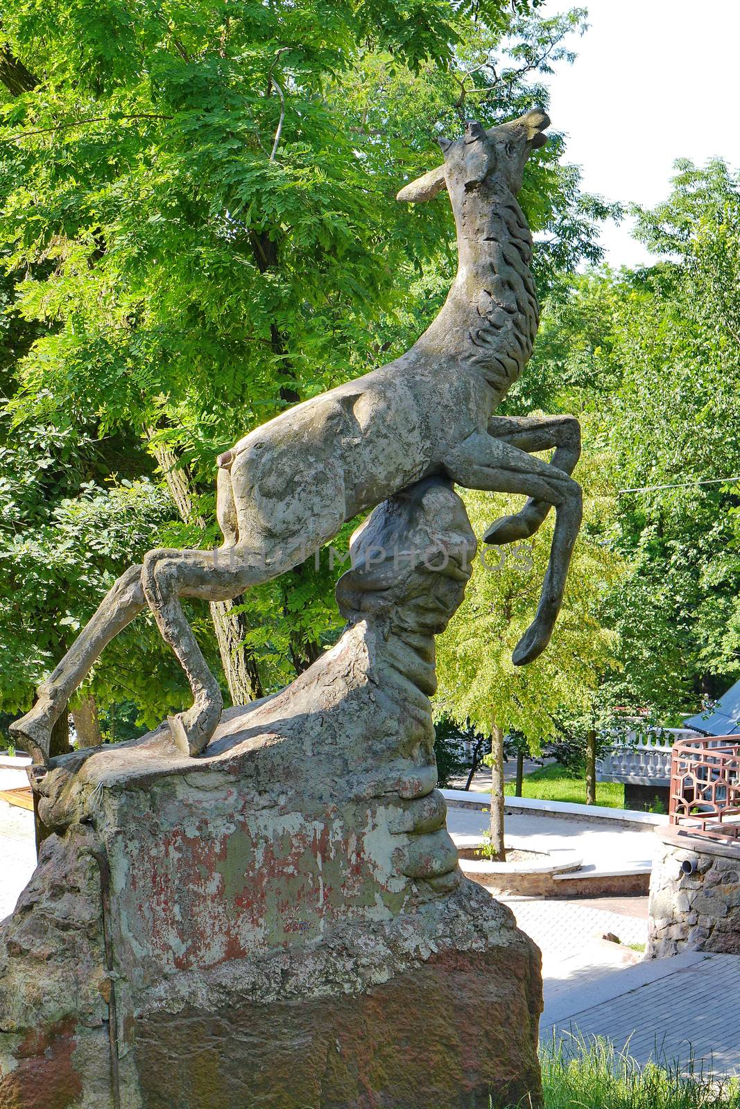 a small pedestal with a beautiful animal against the background of tall green trees