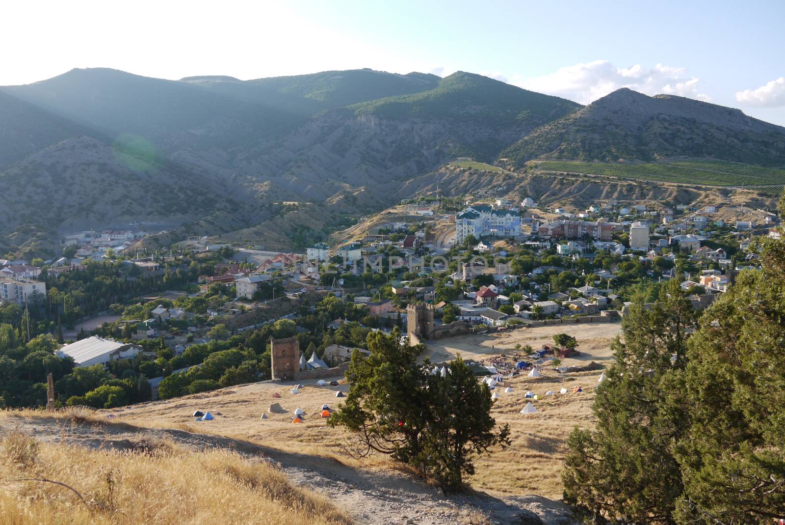 sandy slopes on the background of a cozy town and high mountains covered with grass