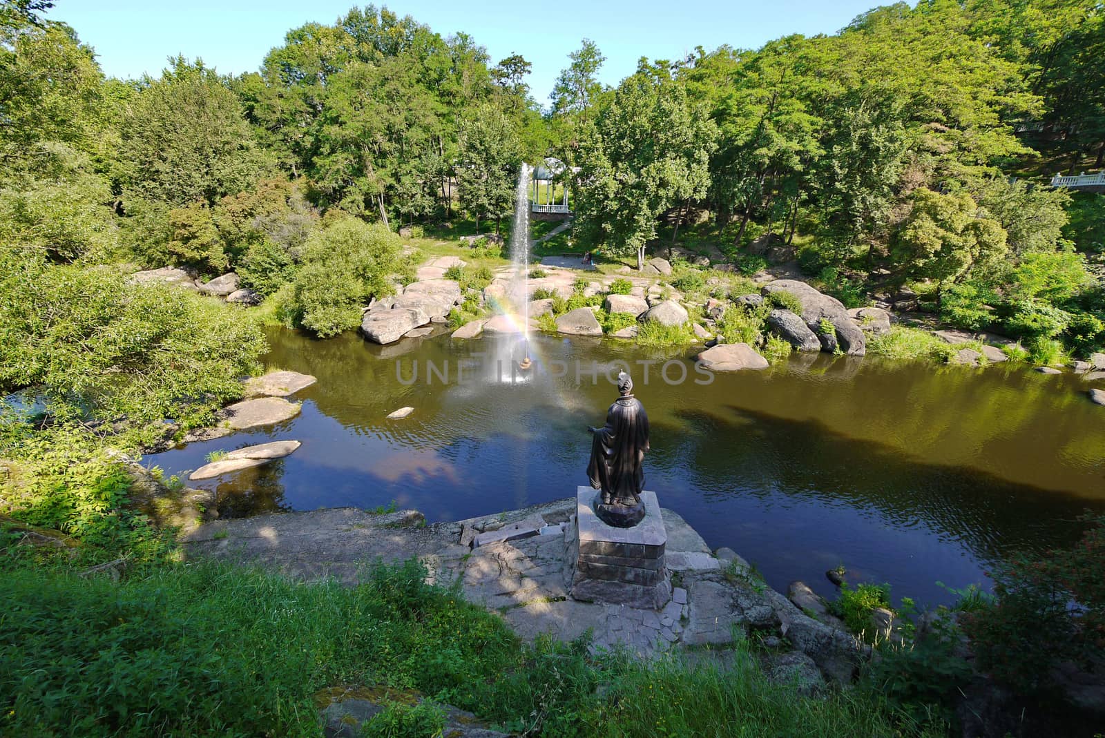 beautiful fountain in the middle of a wide rocky river on the background of dense green trees