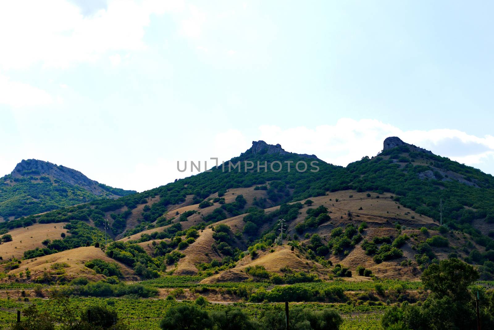 high rocky slopes covered with grass on the background of the cloudy sky