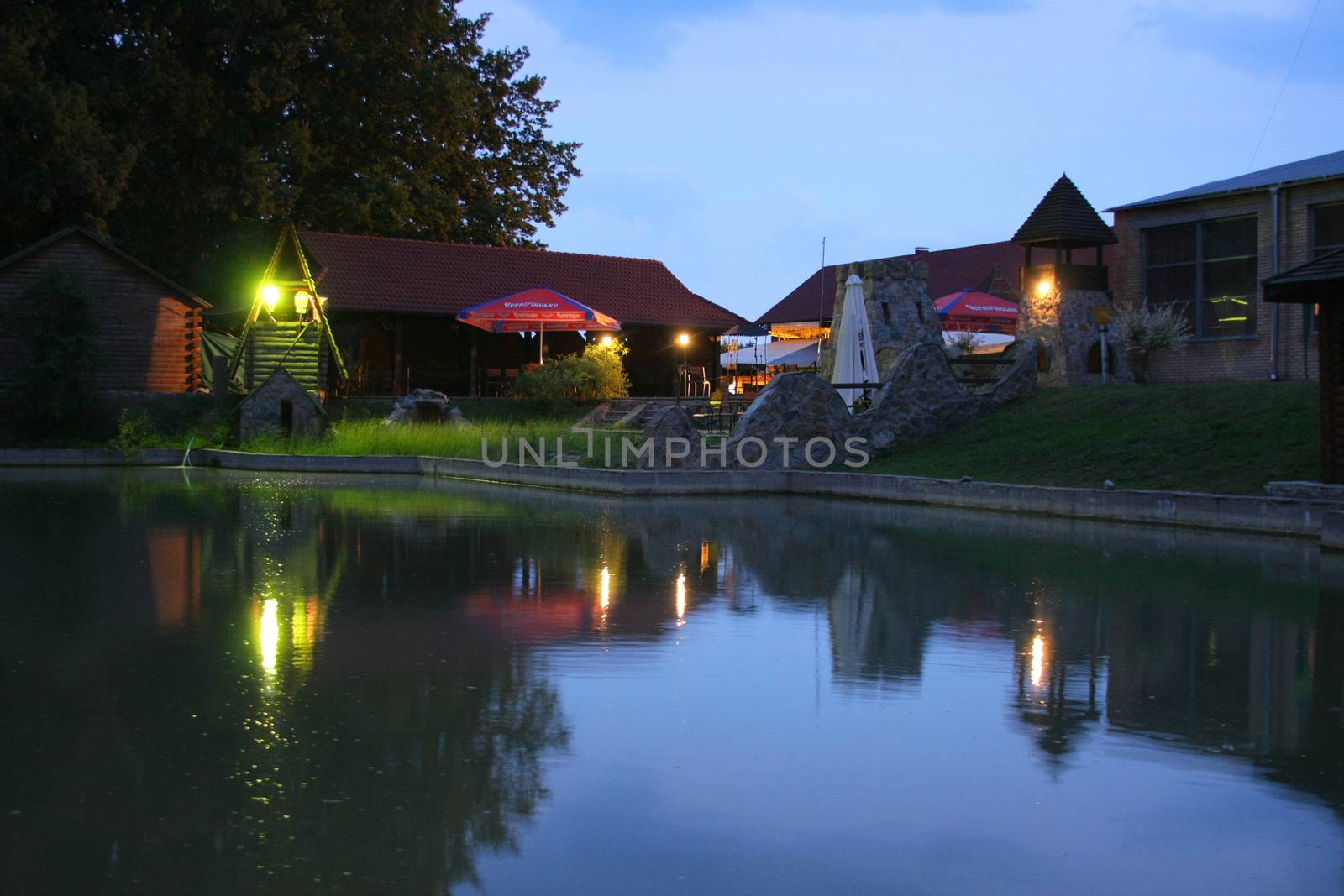 a small lake under the evening sky on the background of a cozy cafe