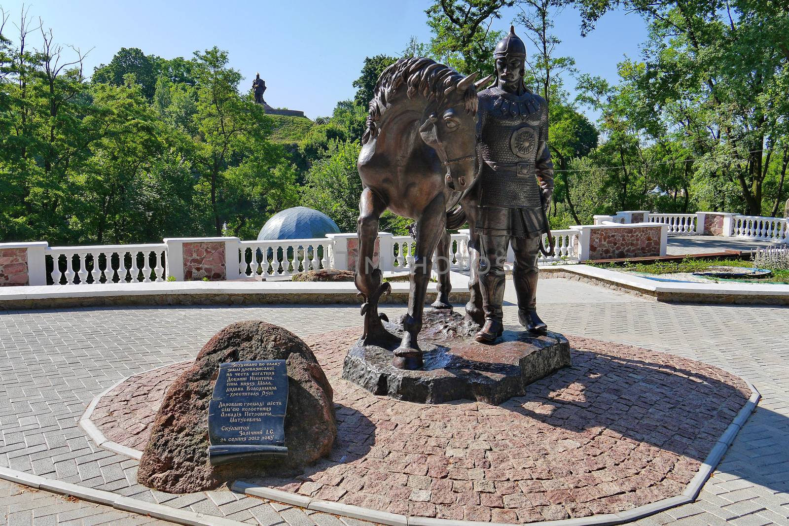 beautiful monument knight with a horse under a blue sky against a grassy slope