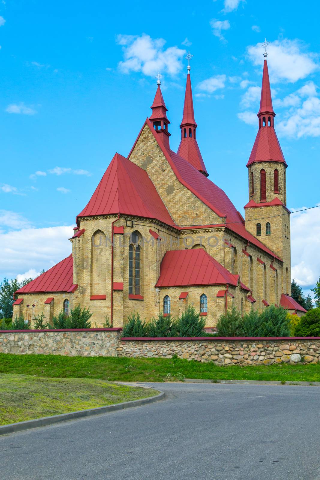 Beautiful brick building with a red roof in a Gothic style on the blue sky background