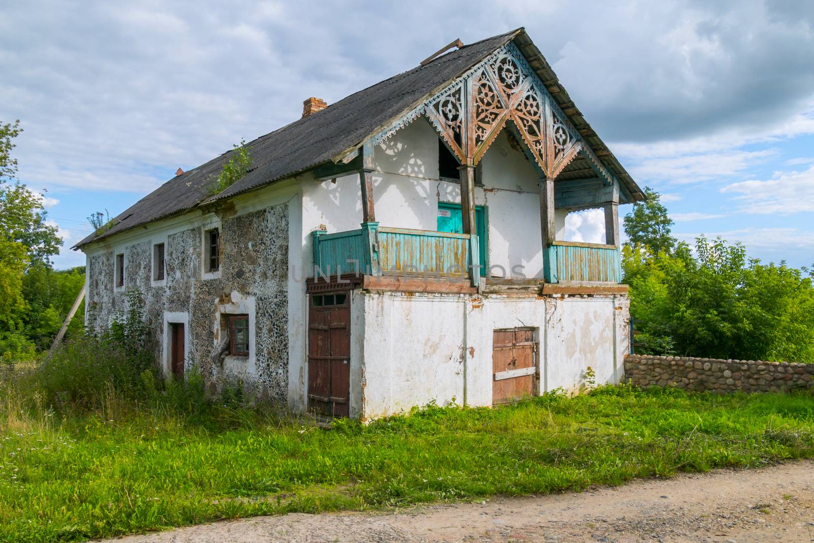 an old abandoned house under a blue sky in the middle of a green lawn