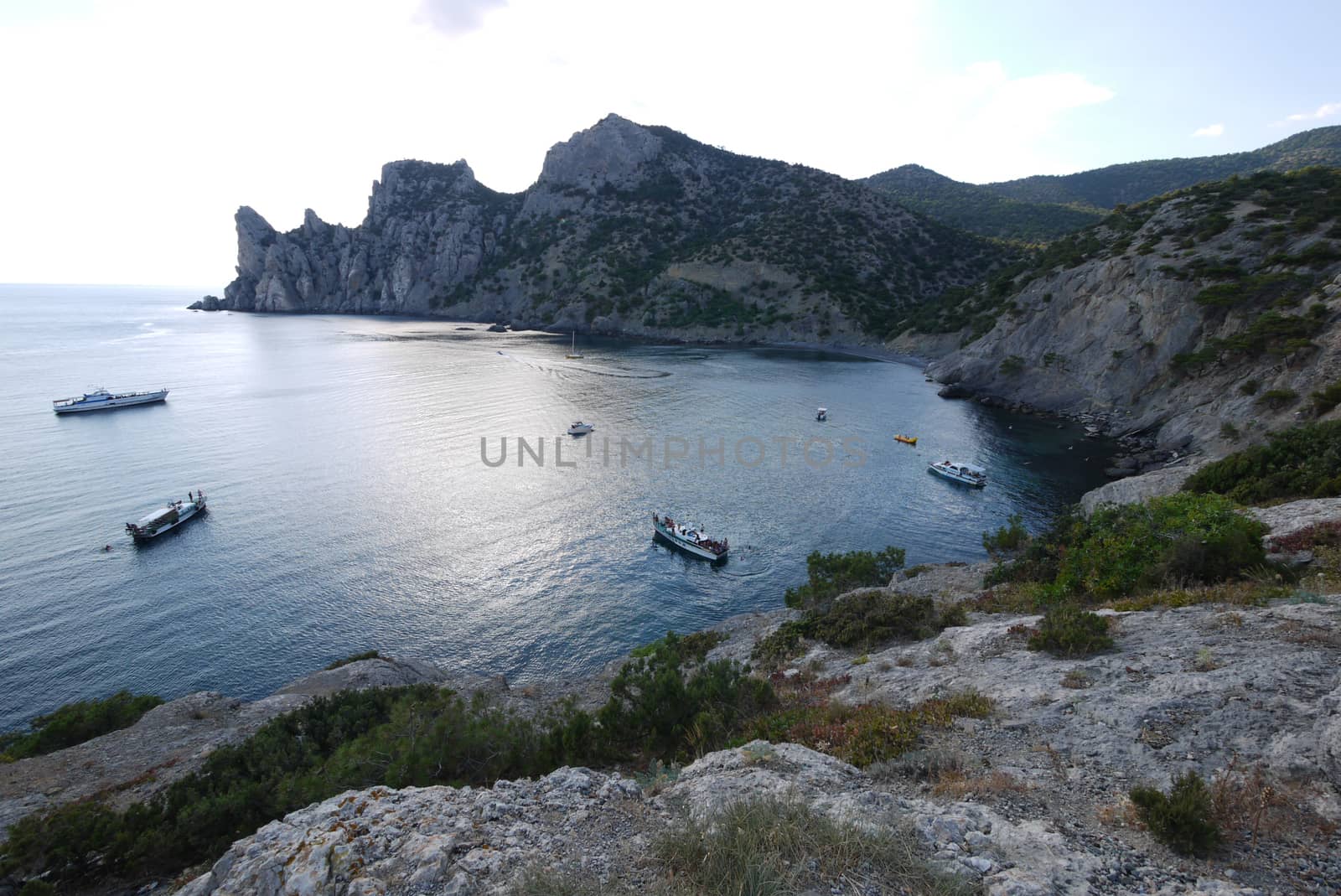 small boats in the middle of a wide bay of the black sea surrounded by high slopes by Adamchuk