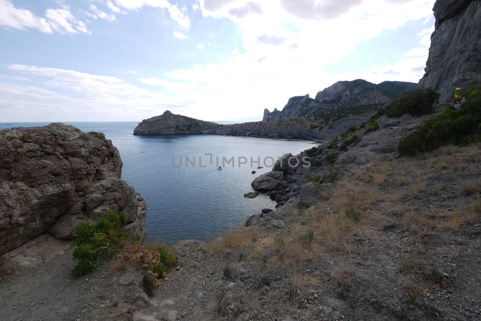 The wide bay is surrounded by high Crimean rocks covered with grass by Adamchuk