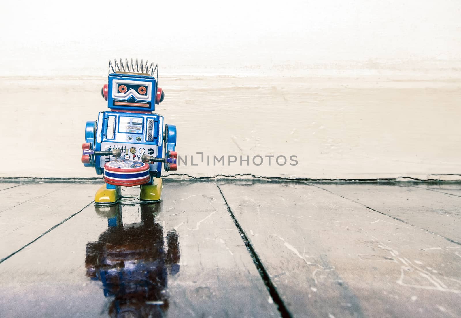 little blue drummer retro robot toy on wooden floor with reflection 
