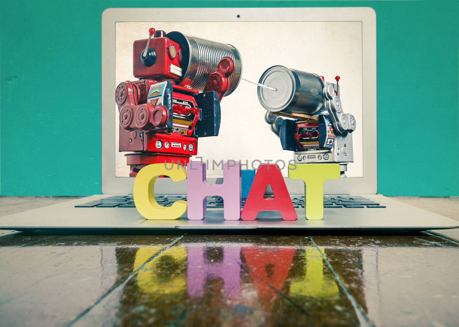 the word CHAT on top of a laptop on a wooden floor  plus two robot toys on tin can phones 