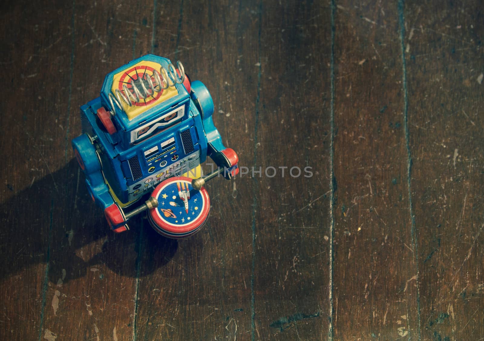 little blue robot drummer on old wooden floor from above 