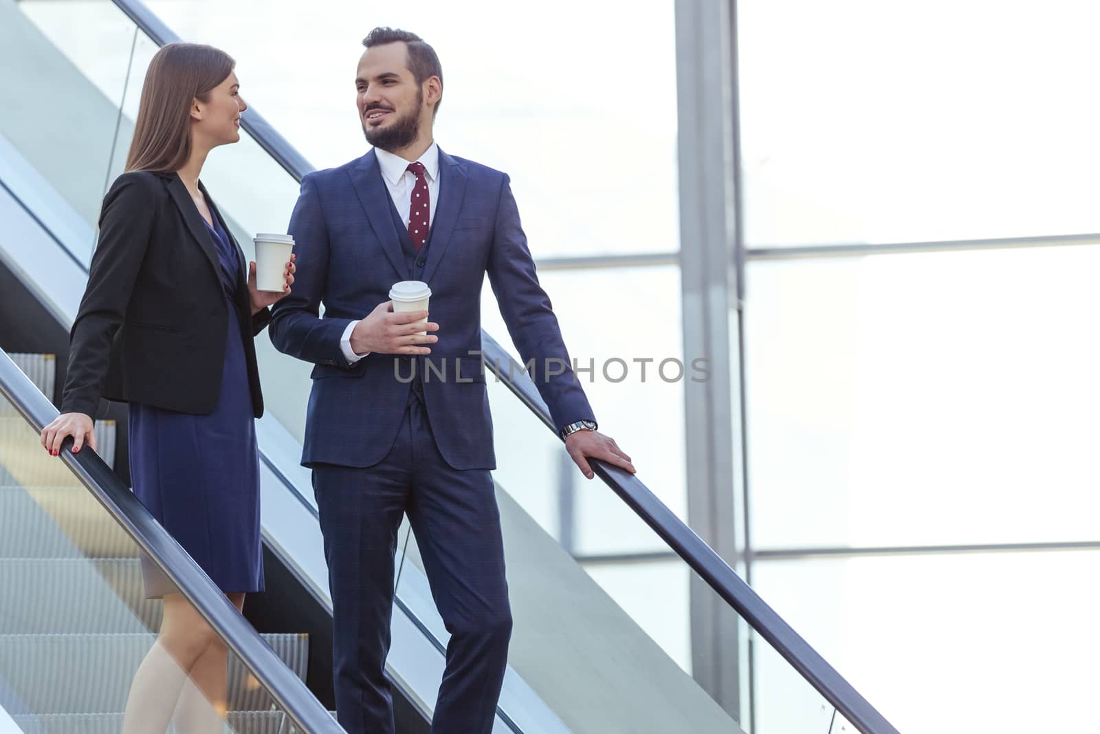 Business partners talking at escalator of business center