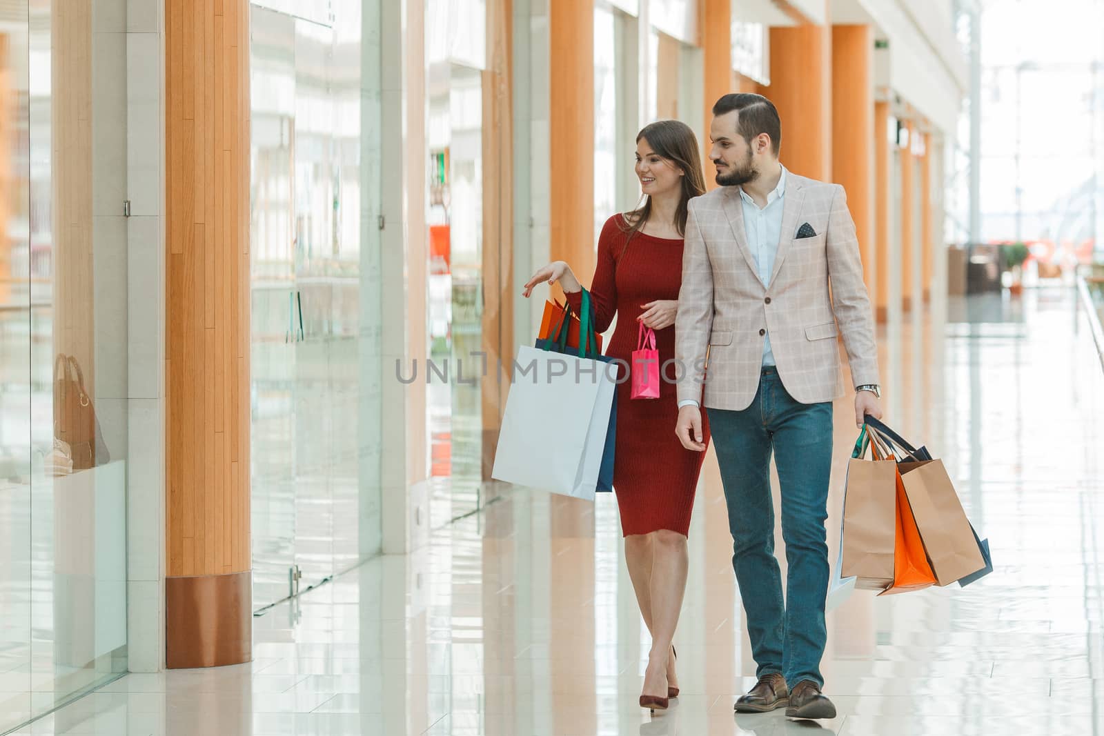 Happy beautiful young couple with shopping bags in mall