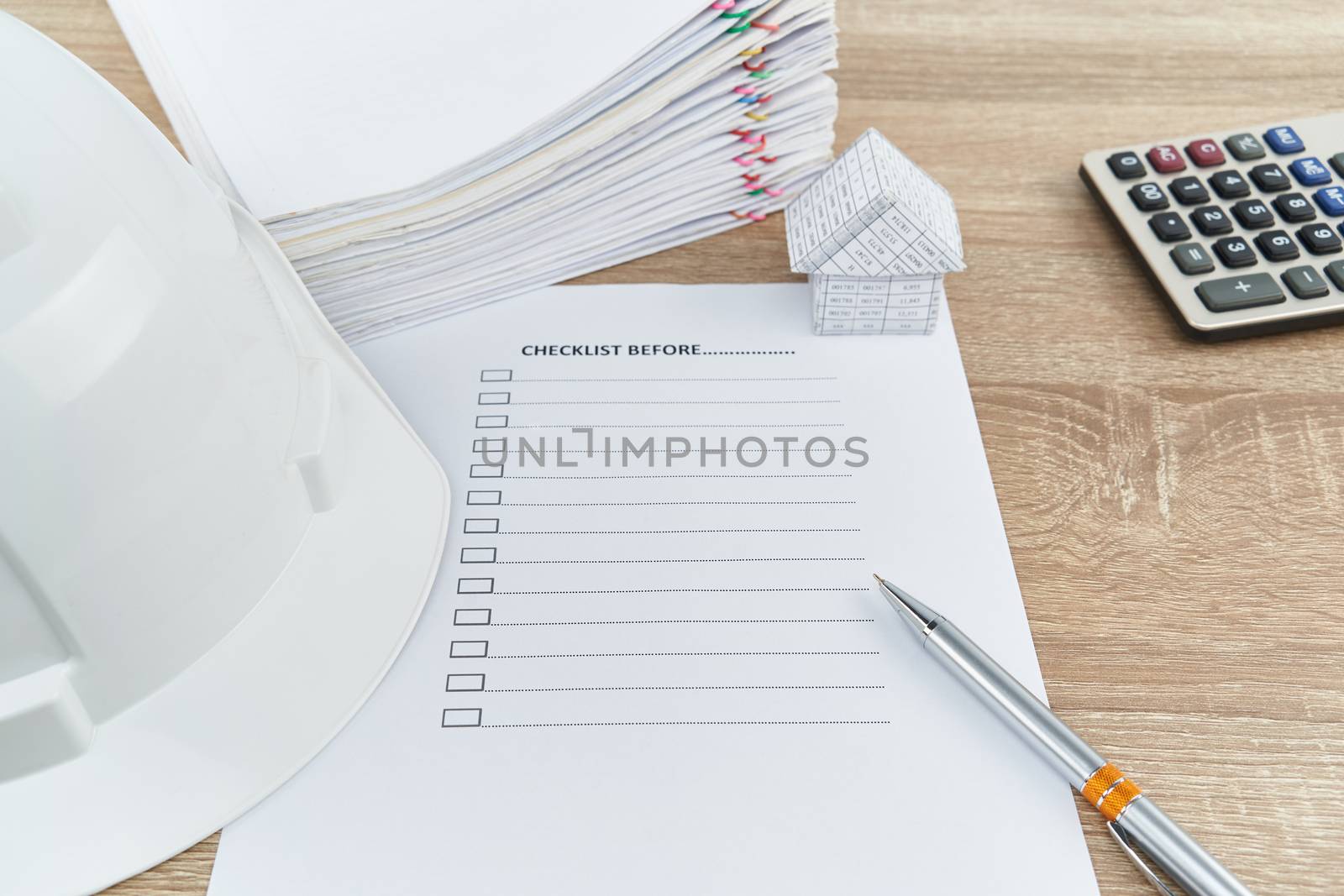 Pen and white engineer hat  with checklist on wooden table by eaglesky