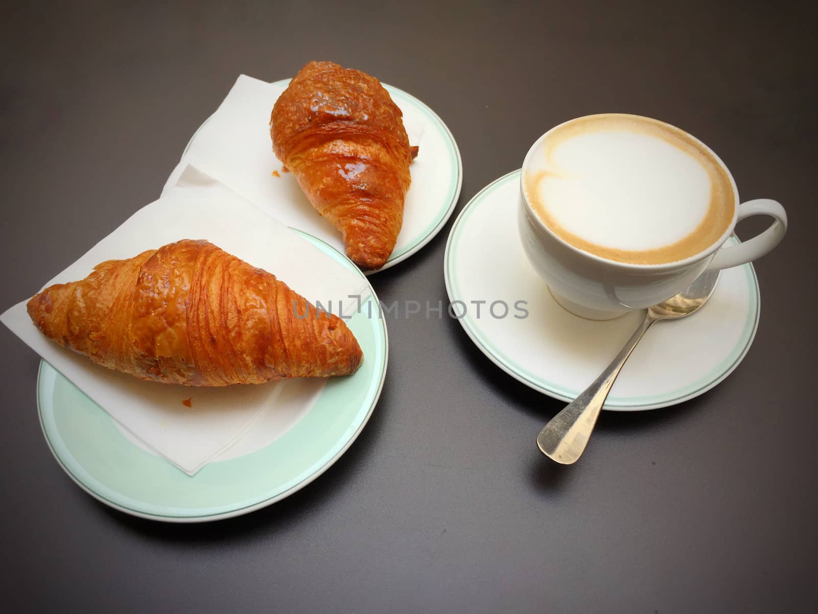 Cappuccino white cup, croissants on dark retro background, selective focus. Breakfast concept