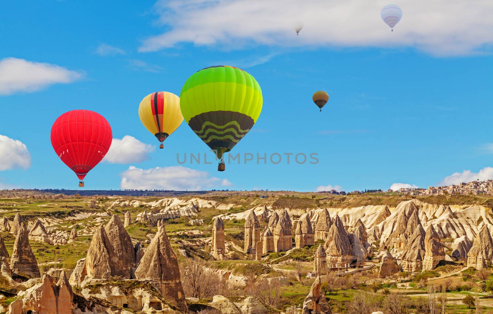 Hot air baloons flying over spectacular stone cliffs in Cappadocia near Goreme, Turkey