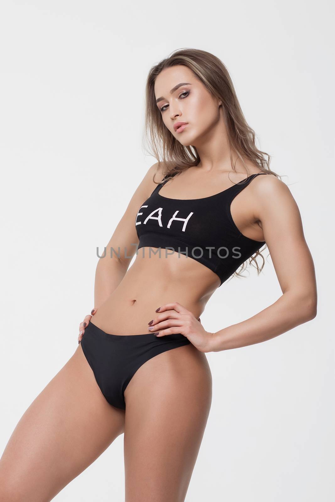 Attractive young woman in black lingerie holding hair with eyes closed on white background