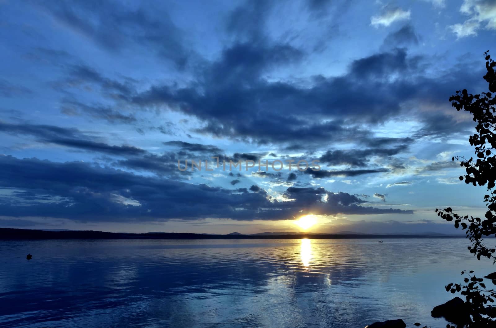 the evening sky over the lake, silhouettes of clouds illuminated by the sun