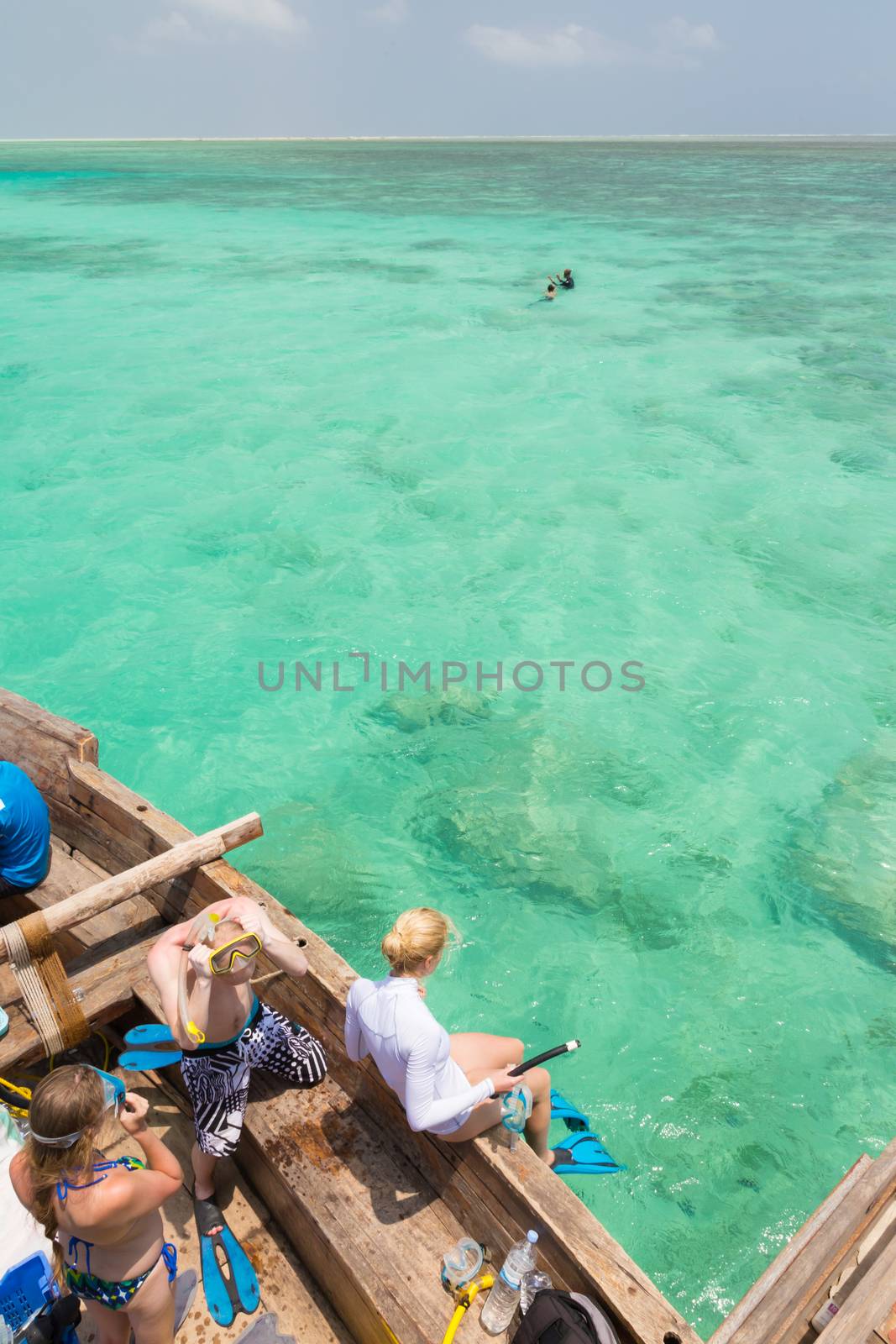 Woman snorkeling in clear shallow sea of tropical lagoon with turquoise blue water and coral reef, near exotic island. Mnemba island, Zanzibar, Tanzania.