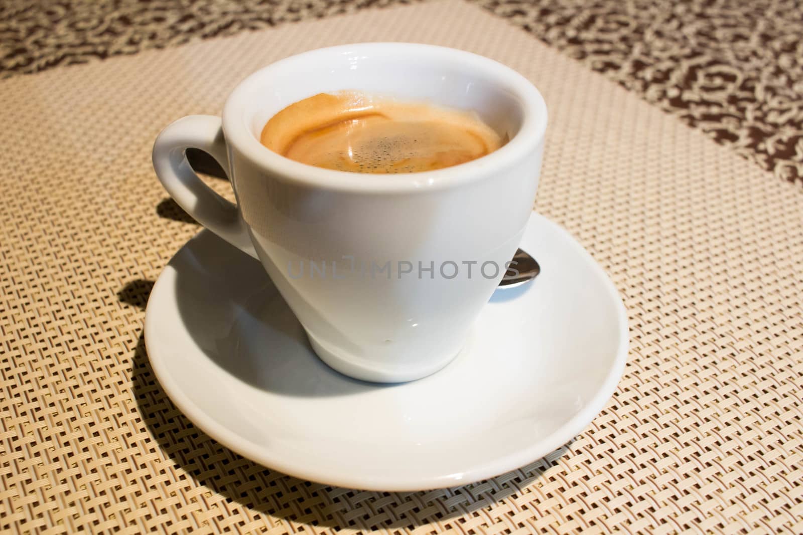 Composition of two cups of coffee on white serving plates with small metal spoons