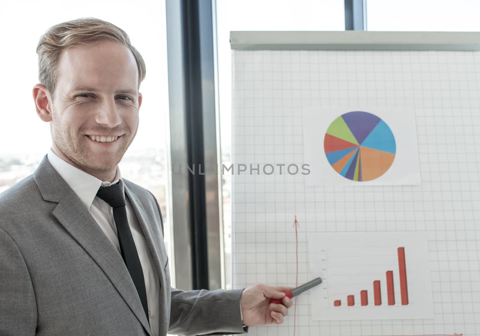 Business man making presentation of reports in diagrams and graphs at flip chart in offfice