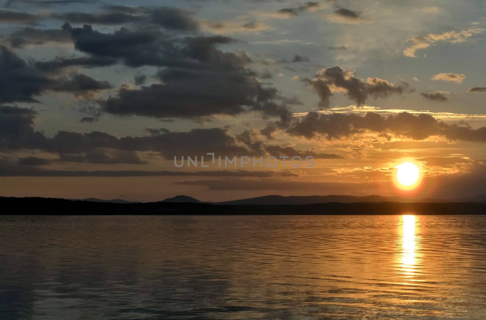 orange sunset over the lake, the sun lights up the clouds