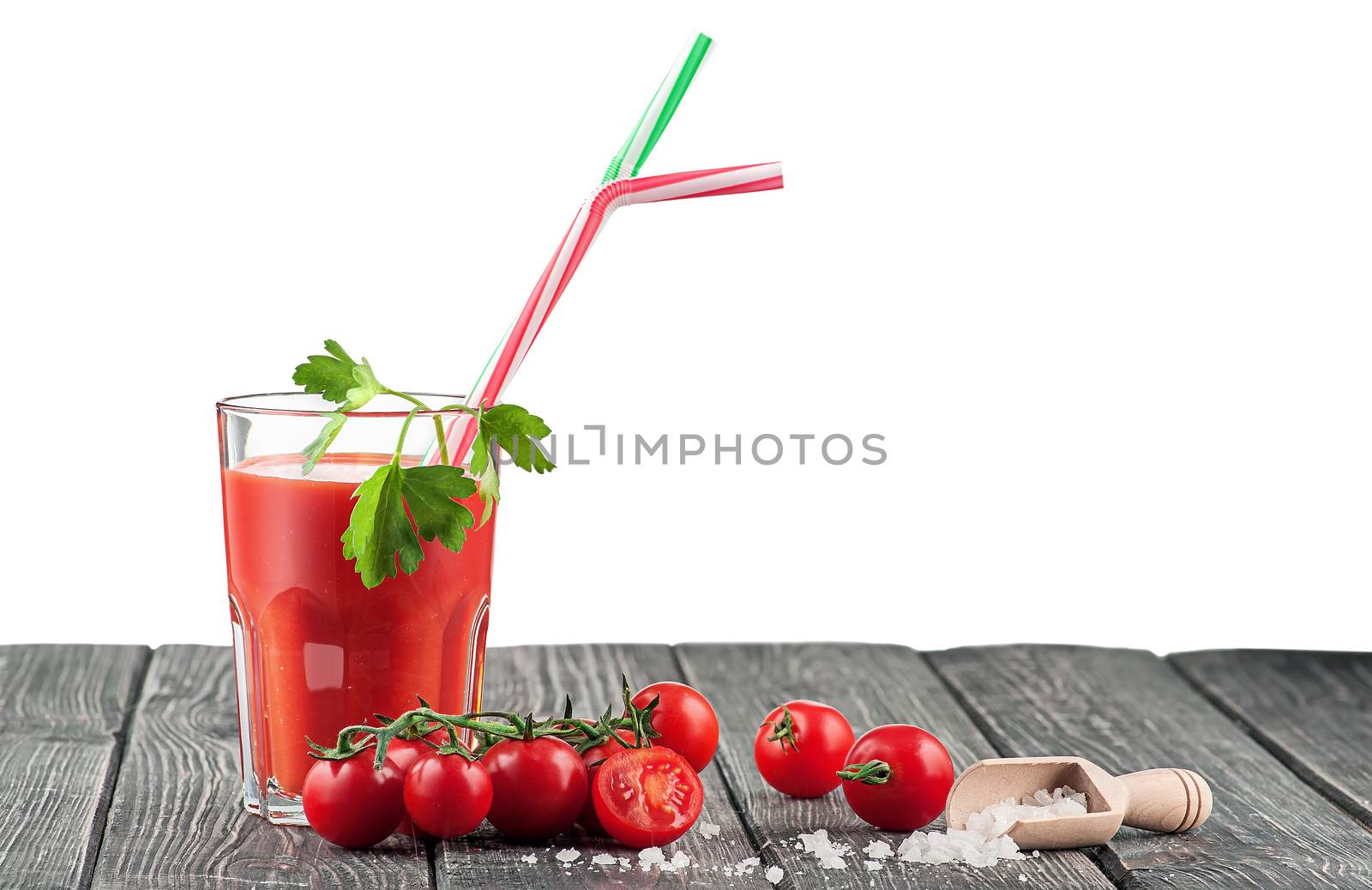 Glass of tomato juice on a wooden table. Salt on a wooden table next to cherry tomatoes. Isolated on white background.