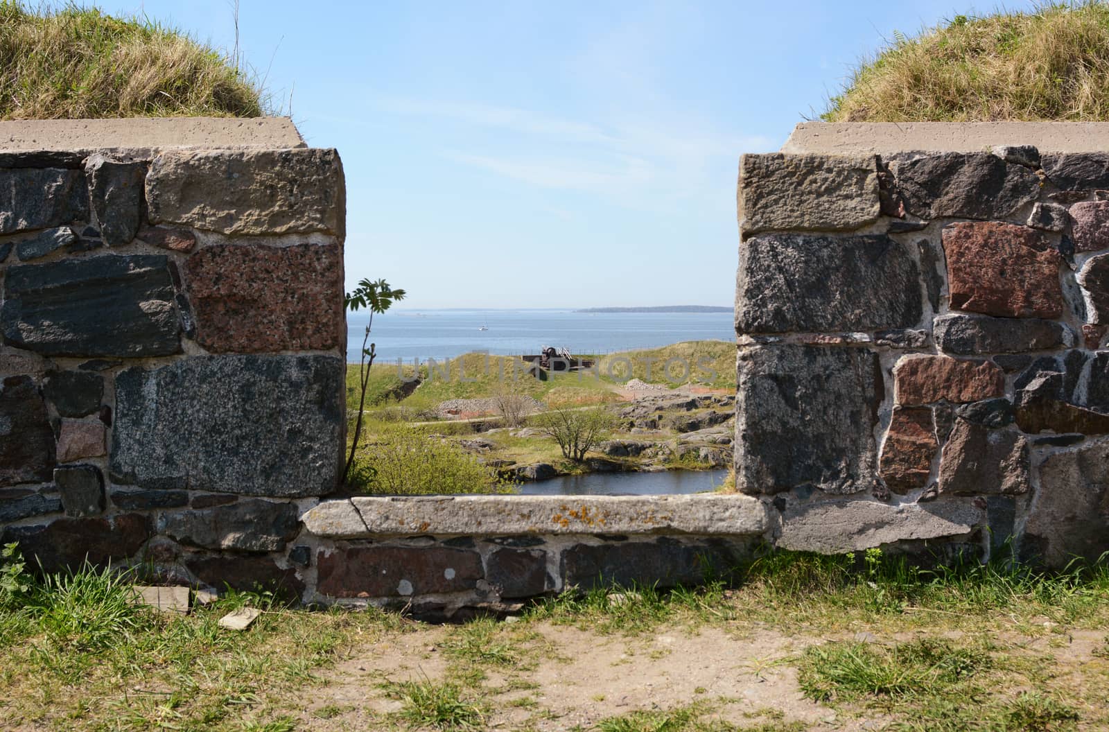 View out to sea through thick castellations in a defensive stone wall on Suomenlinna sea fortress