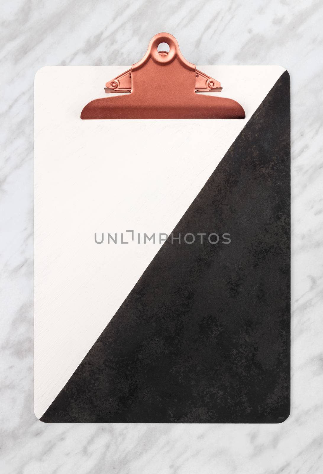 Stylish black and white clipboard with rose gold clip, on marble background.