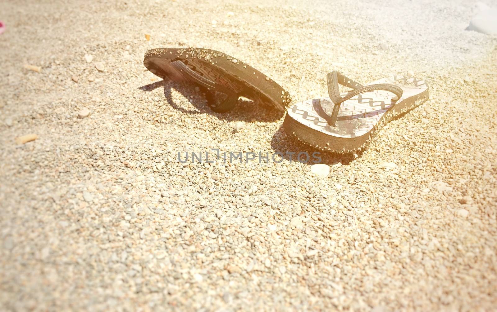 A pair of flip-flops on a stony beach