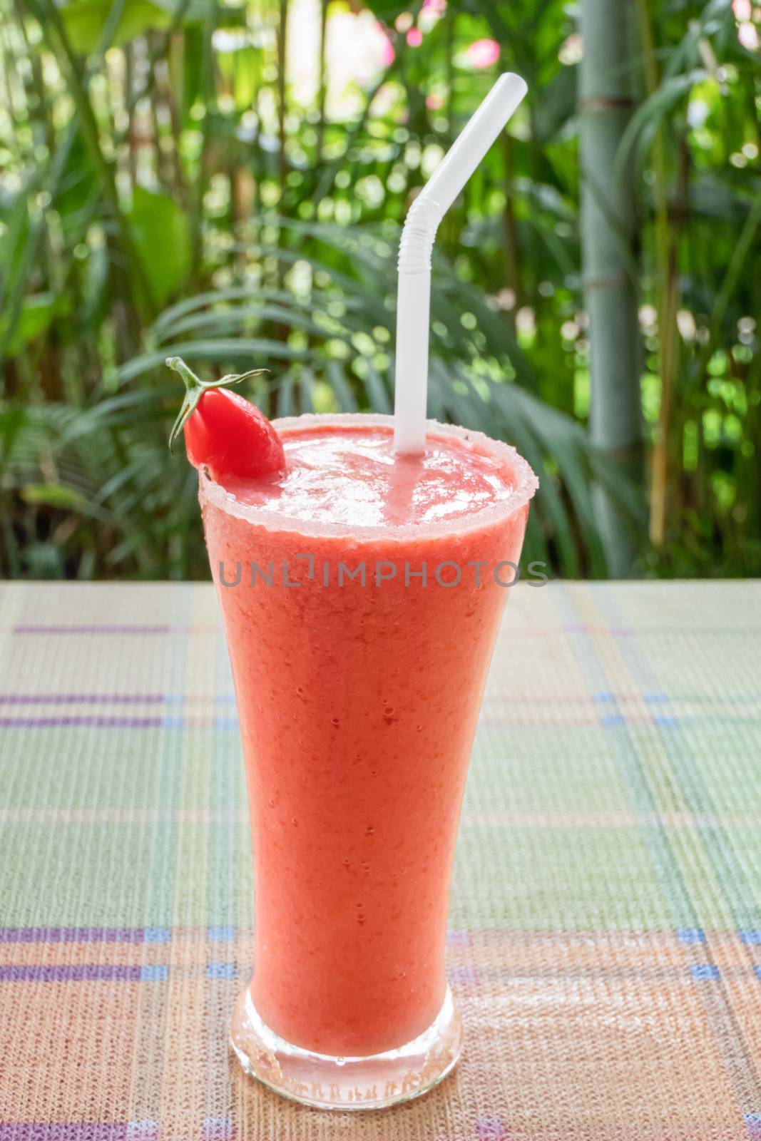 Healthy smoothie in a glass with tomato on a nature background