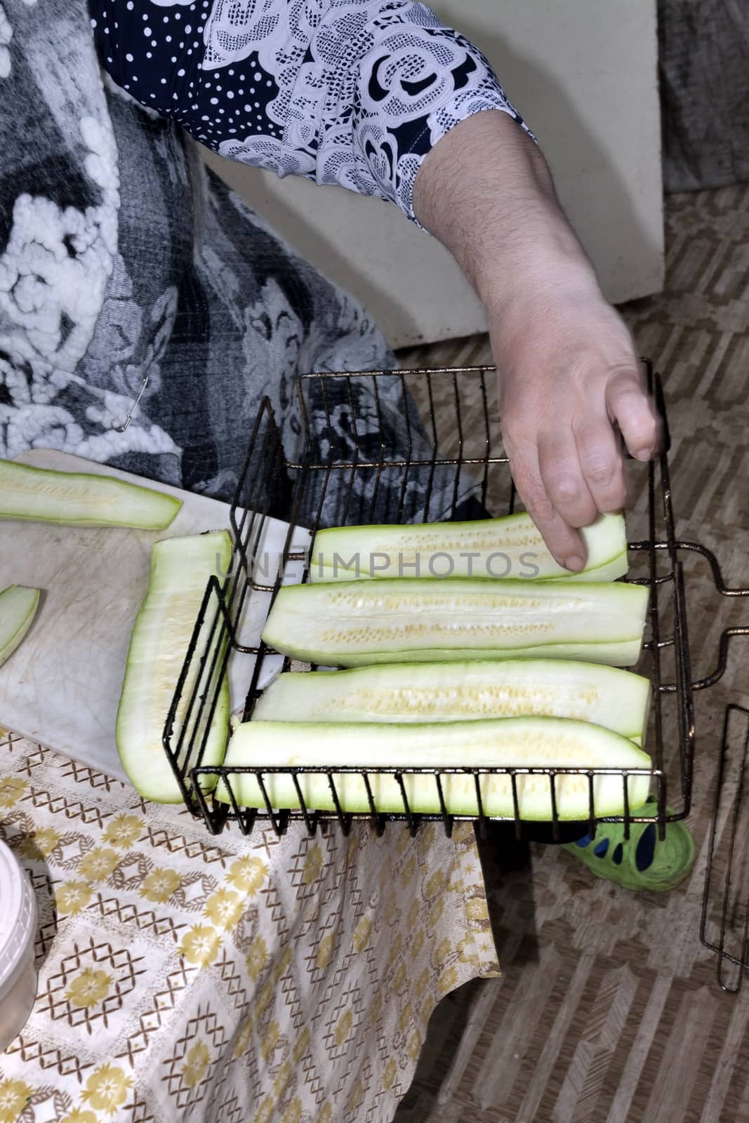 placing the cut zucchini on the grill, the hands of the cook are visible