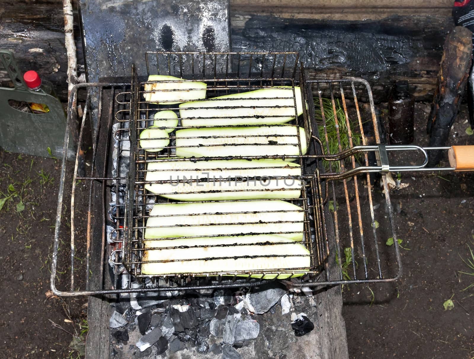 zucchini just started roasting on the grill, zucchini have just started to fry on the grill, visible red coals