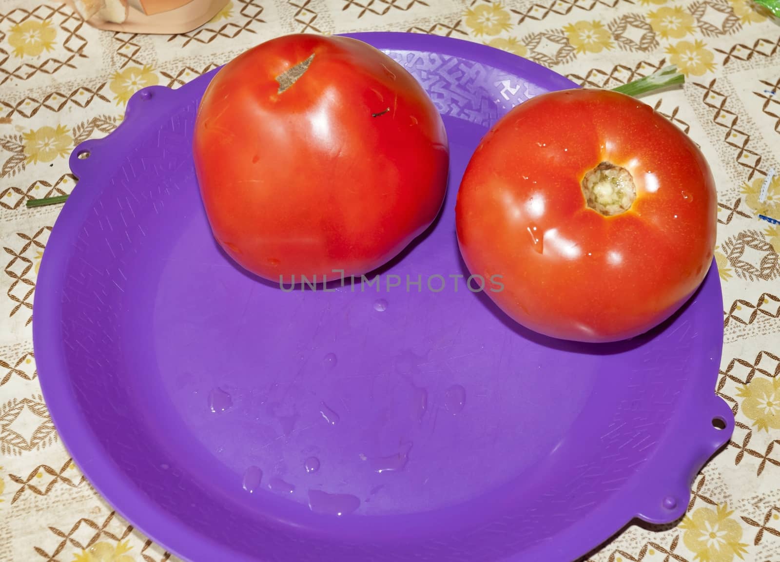 two red tomatoes on a purple plate